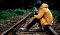 young man sitting on the railroad tracks looking at the pictures in his camera